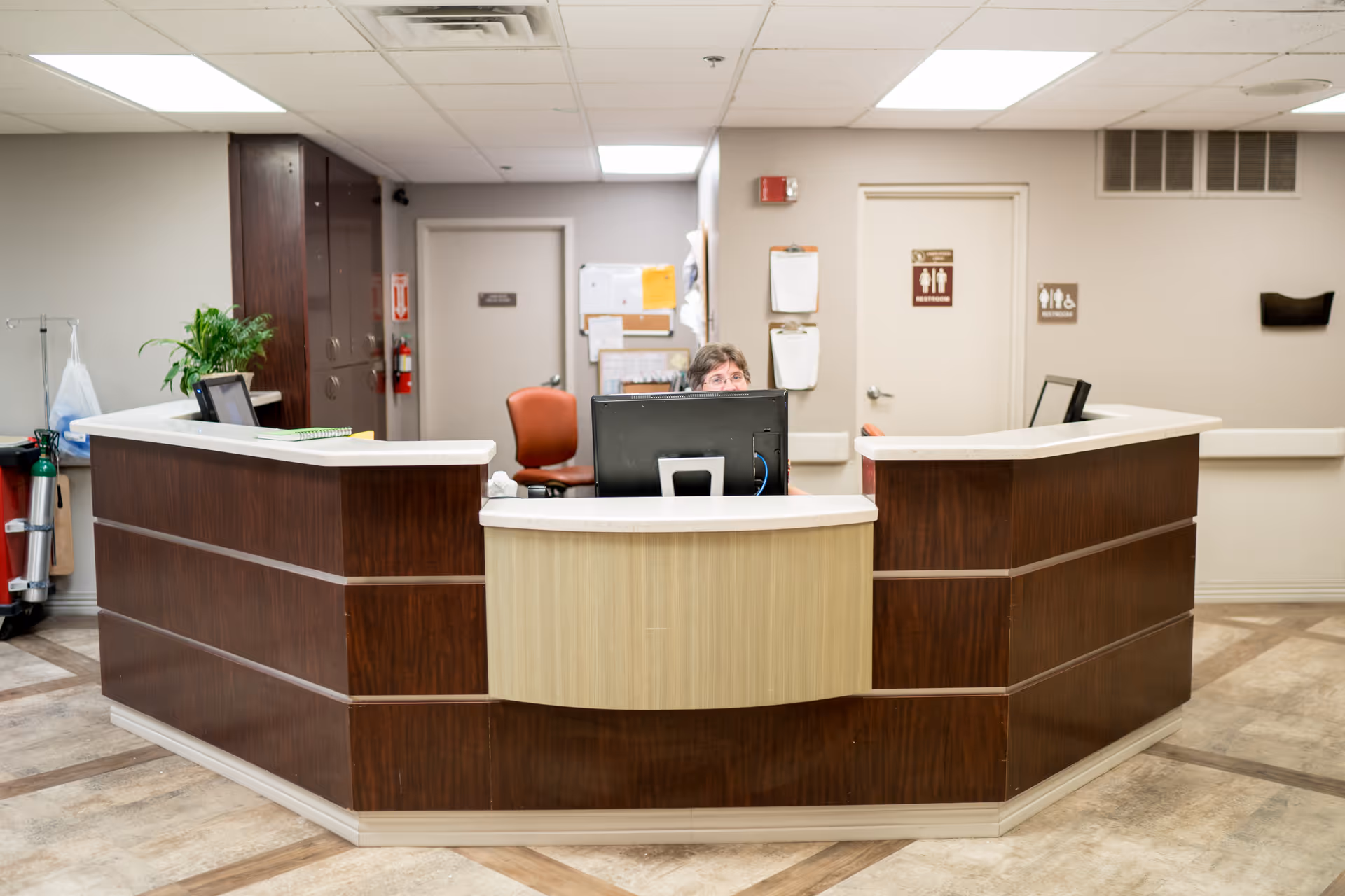 Curved reception desk in a senior living facility lobby, with a staff member behind it.