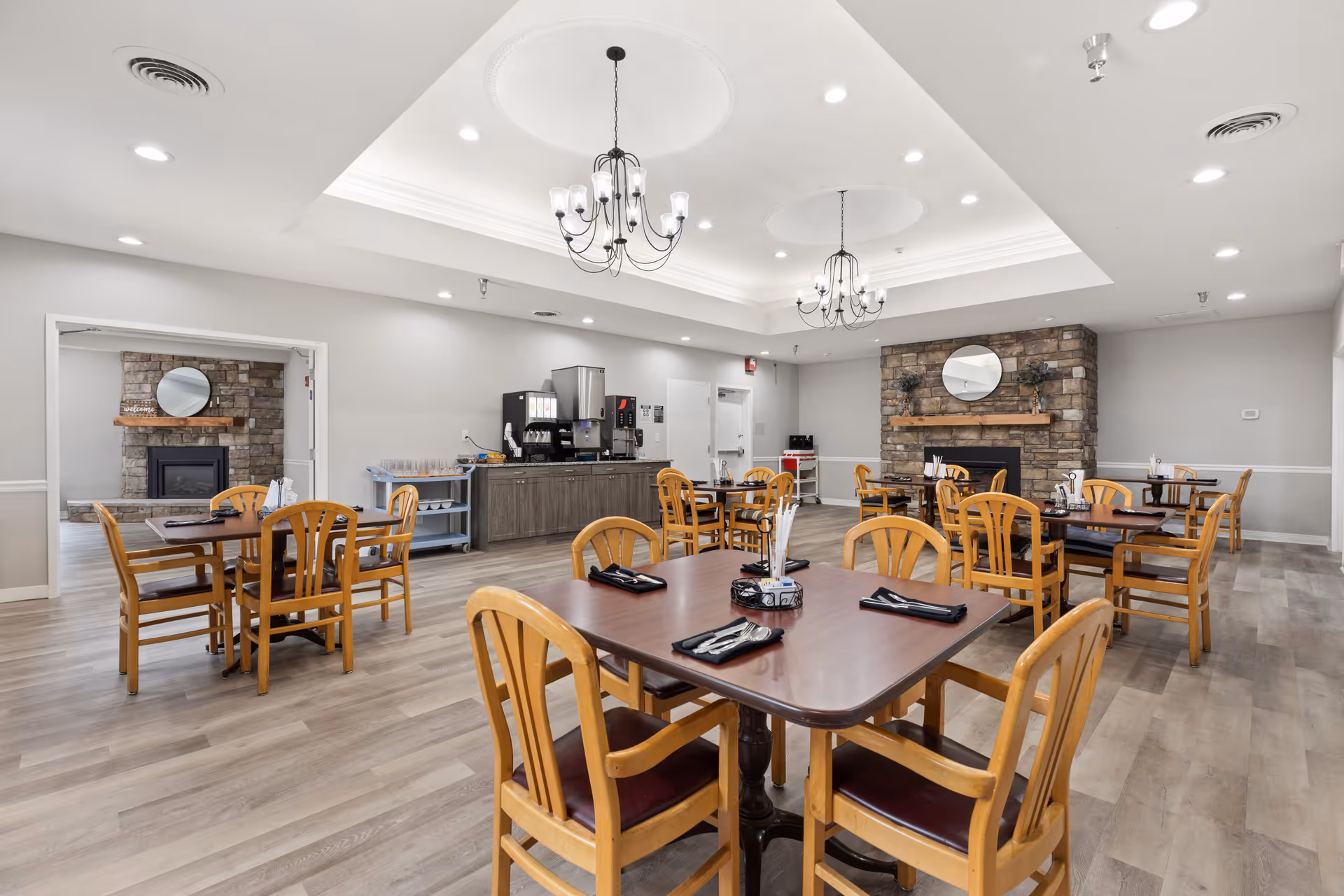 Spacious dining area with wooden tables, chairs, and stone fireplaces.