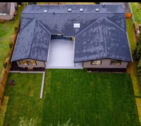 Aerial view of a single-story senior living home with a green lawn and dark roof