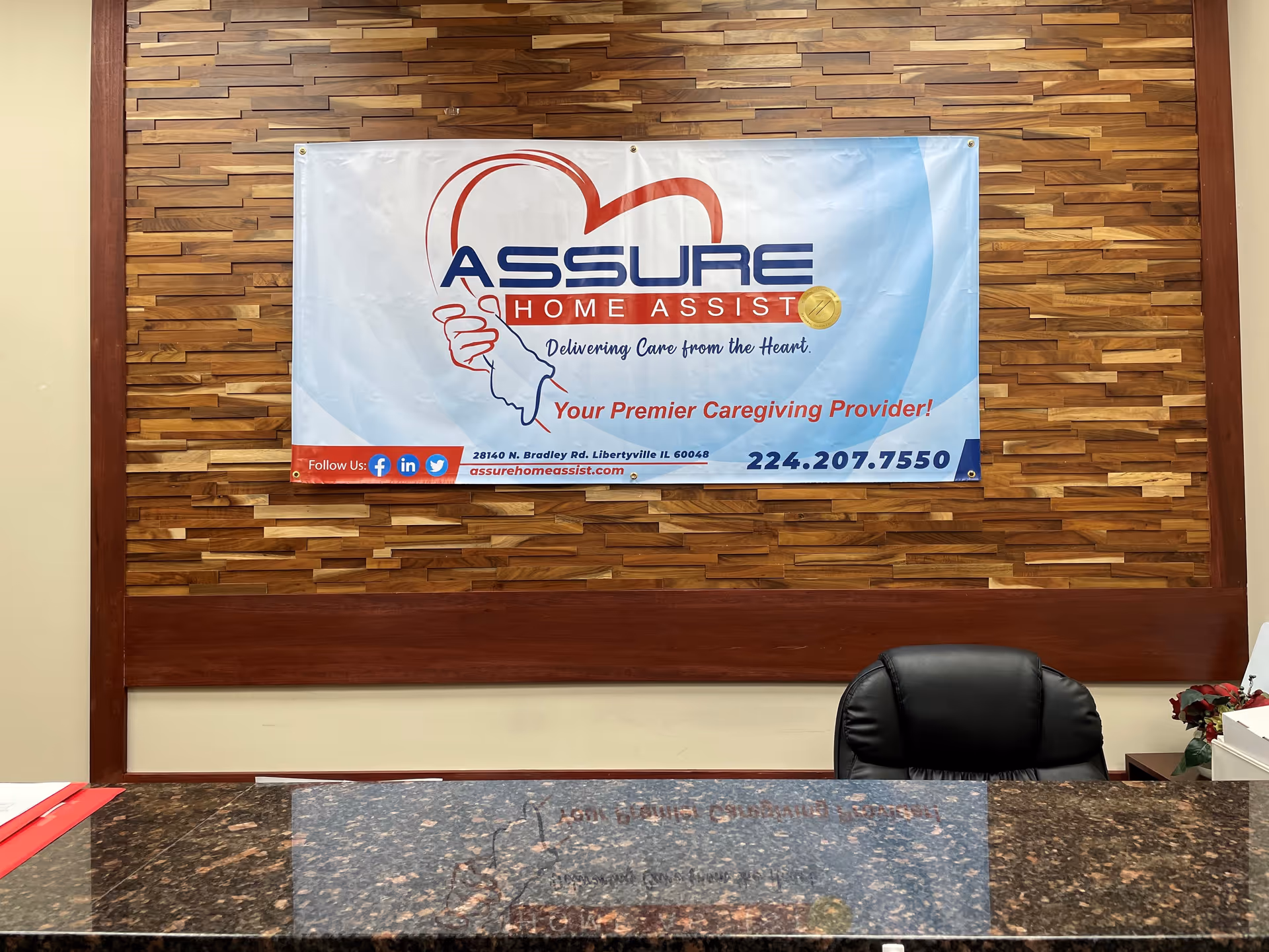 Reception area with a banner on a wood-paneled wall behind a glass-topped desk