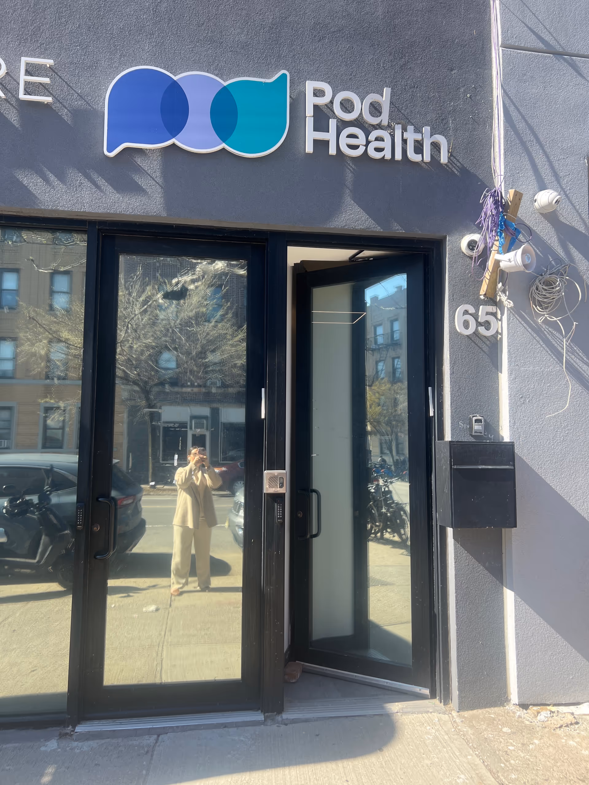 Exterior facade of Pod Health with glass doors and a prominent logo sign.