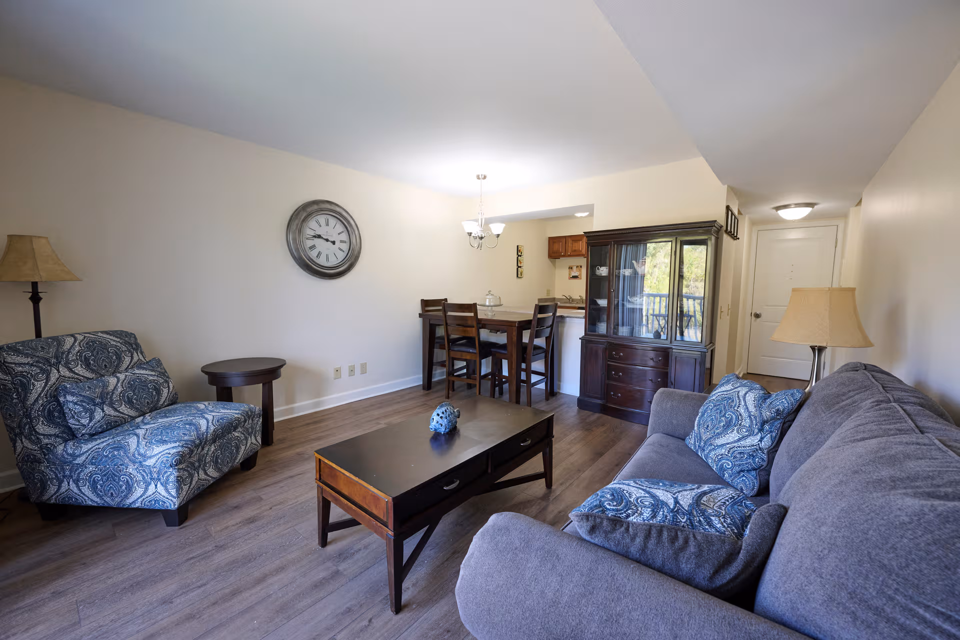 Living room area with sofa, armchairs, coffee table, dining table, and a china cabinet.