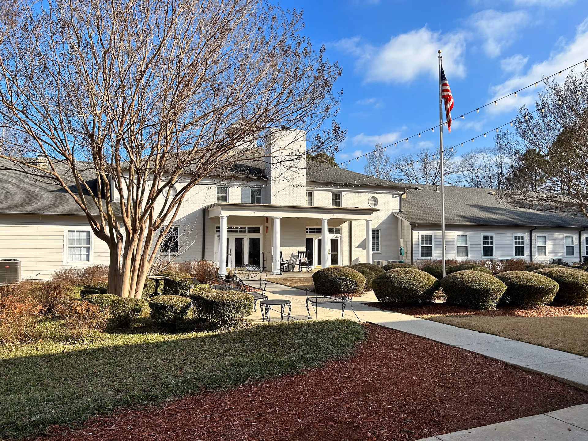 Exterior view of SummerHouse Byrd Springs front entrance with flag and outdoor seating.