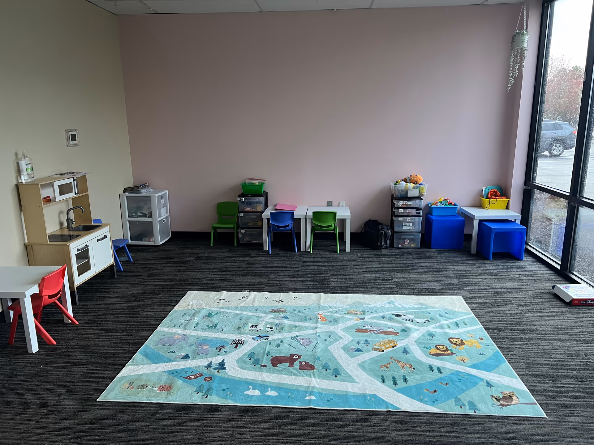 Indoor playroom with child-sized furniture and a colorful rug.