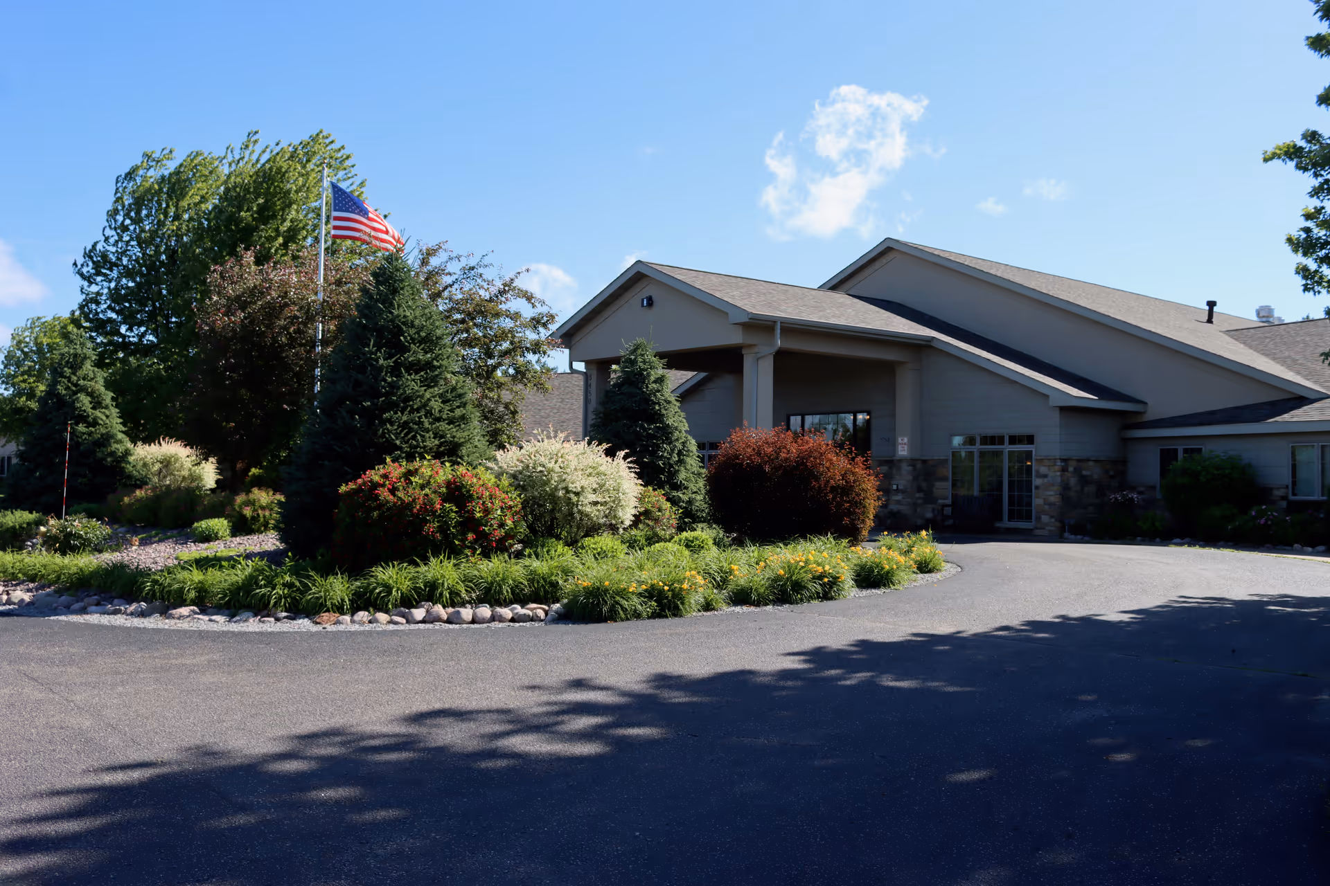 Exterior of The Lodge at Whispering Pines showing landscaped roundabout and American flag.
