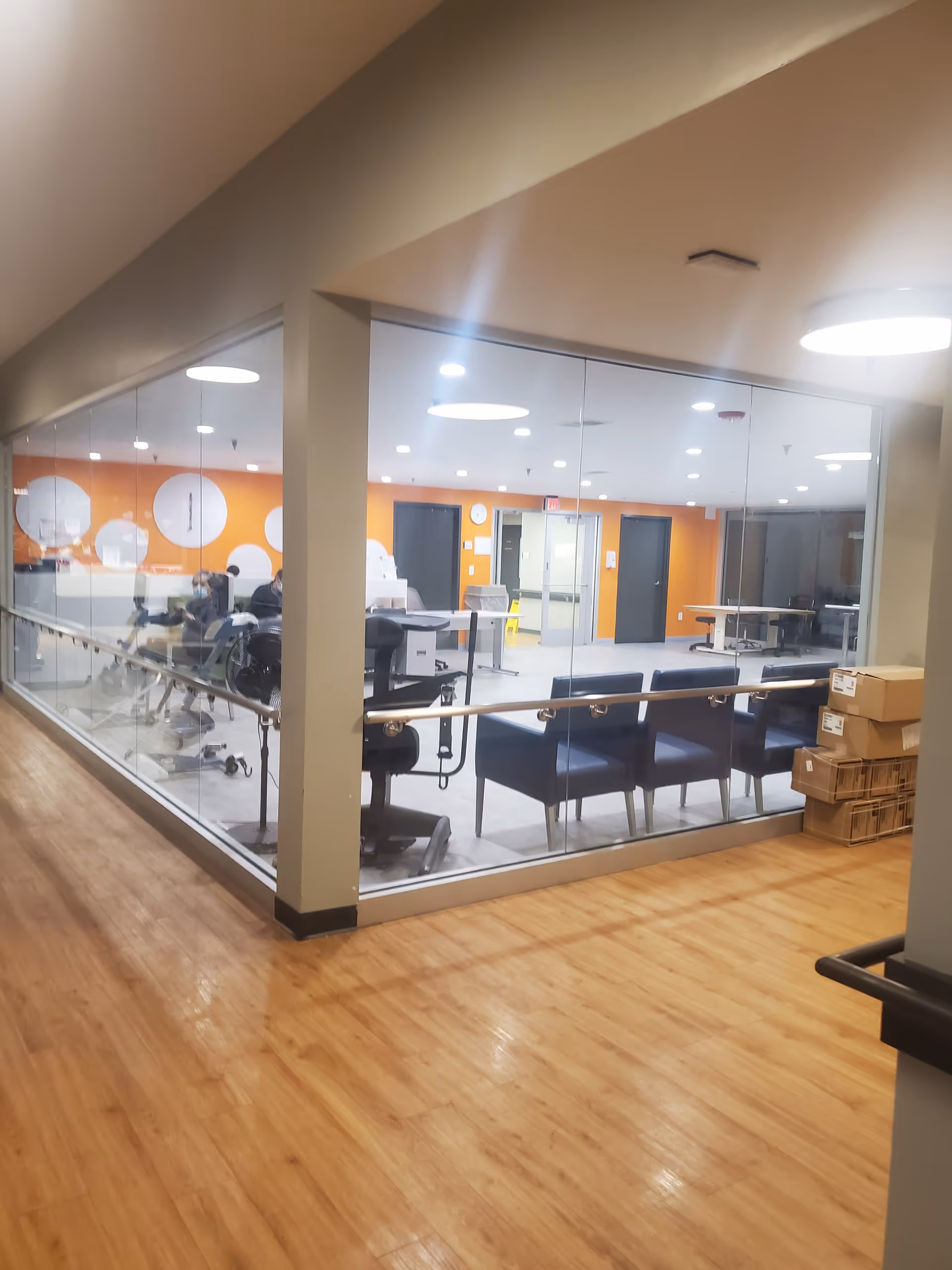 Glass-walled exercise room inside Avantara Elgin with orange accent wall and equipment.