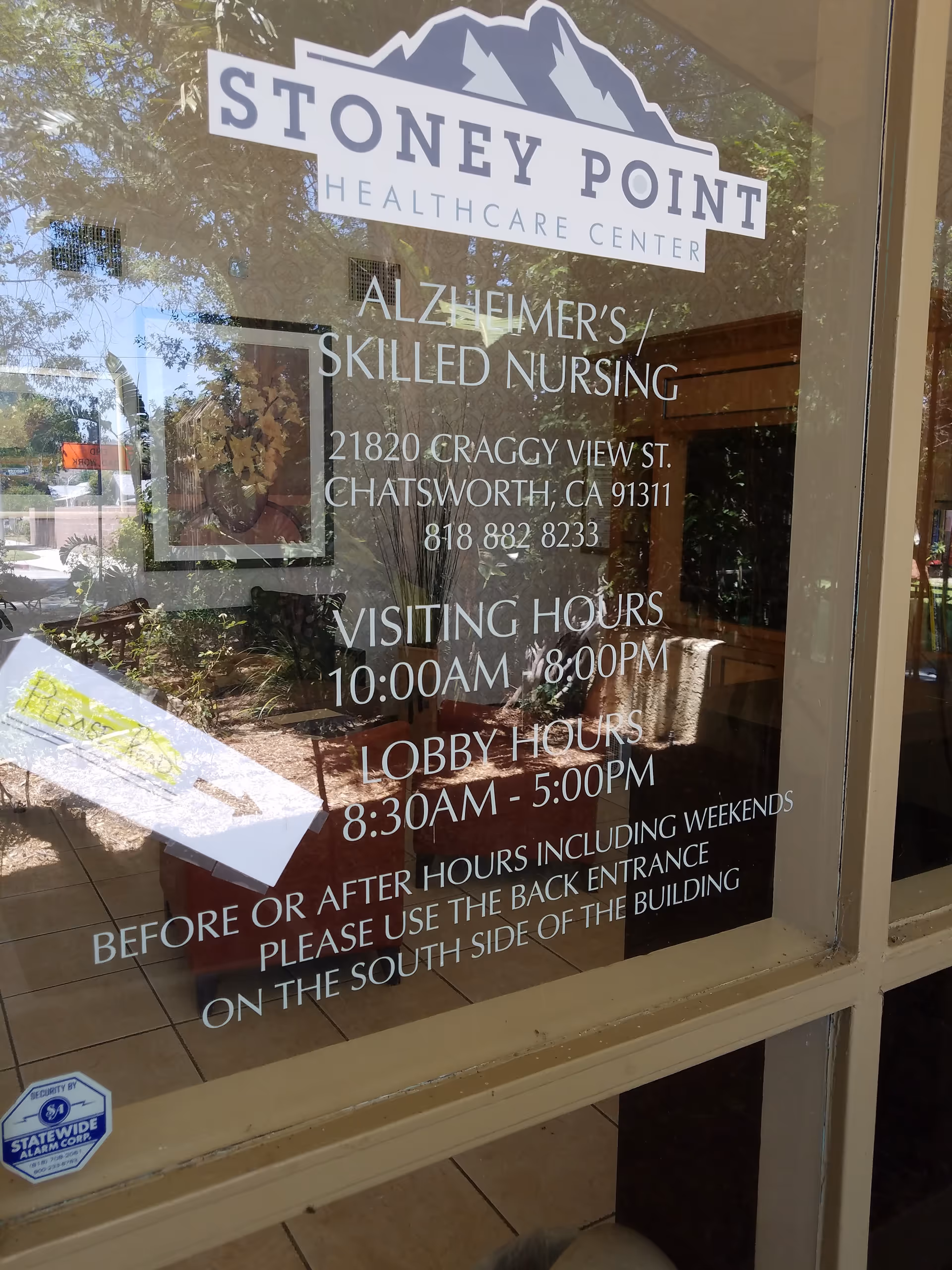 Glass door with Stoney Point Healthcare Center logo and hours, reflecting the exterior.