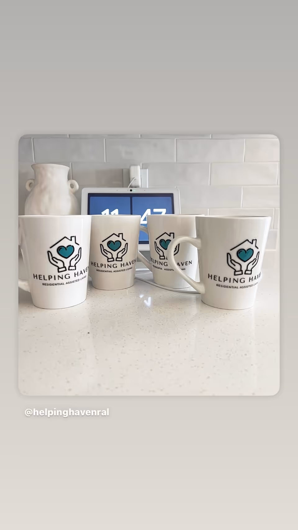 Row of white mugs with Helping Haven logo on a kitchen counter.