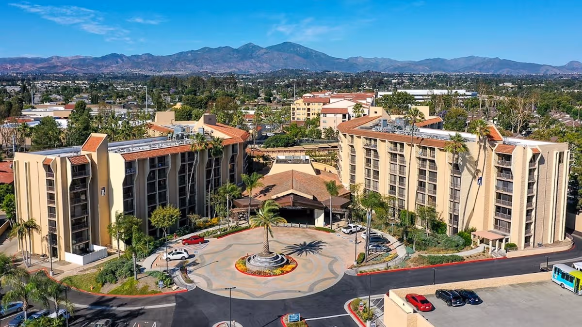 Exterior view of Meridian at Laguna Hills campus with beige buildings around a circular driveway.