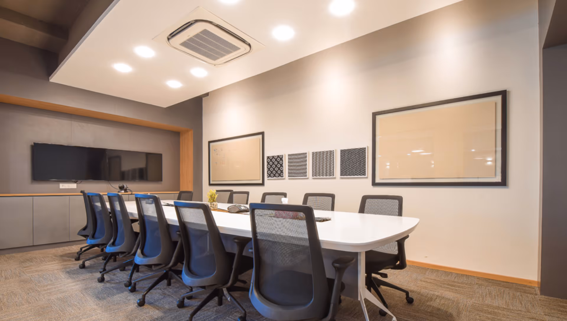 A modern conference room with a long white table, office chairs, and wall art.