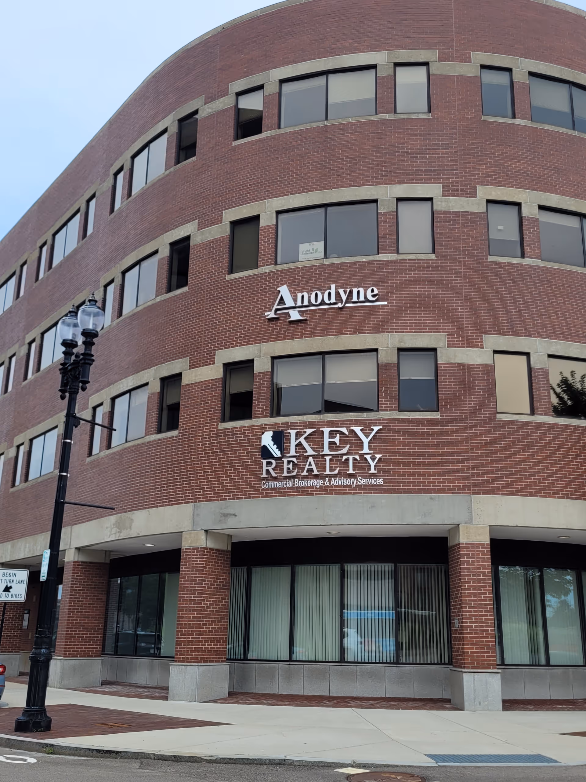 Brick multi-story building facade with Anodyne sign and storefront windows along a sidewalk.
