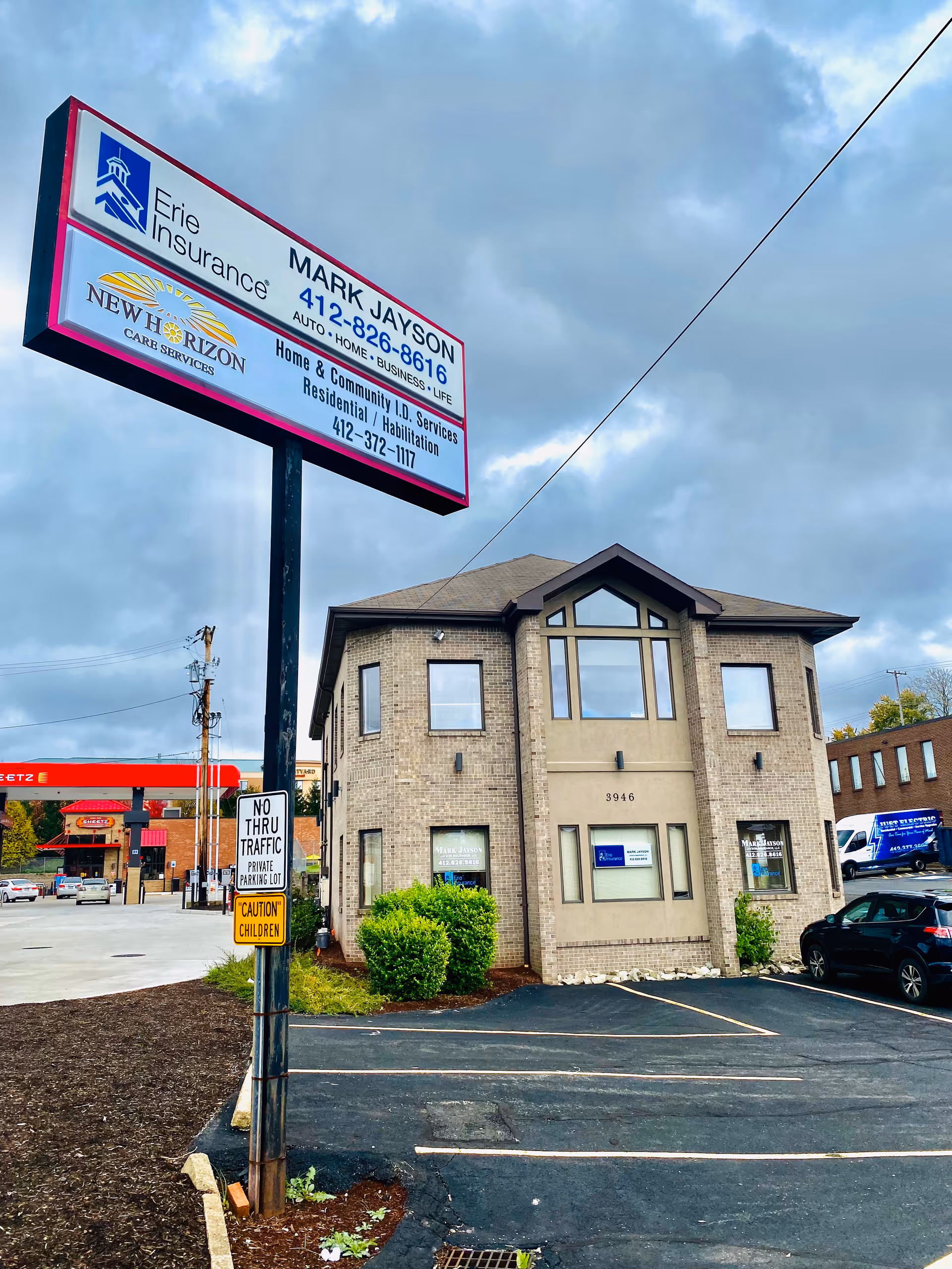 Brick senior living facility with a large roadside sign and parking lot.