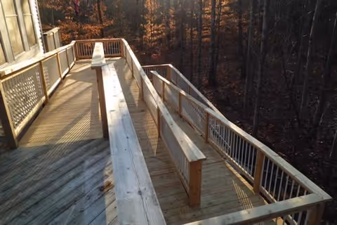 Wooden outdoor deck with benches extends from the building toward a wooded area.