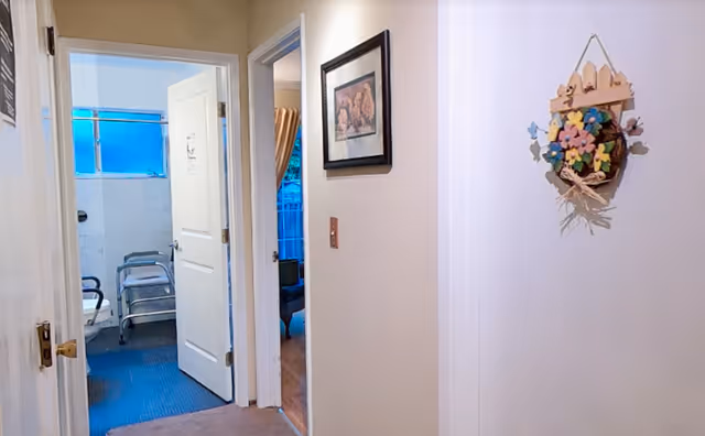 Hallway inside Hope's Creek Retirement Living showing an open bathroom door and decorative wall art.