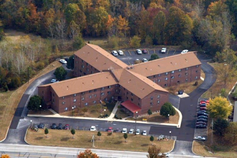 Aerial view of a brick senior living facility with parking lots and surrounding trees.