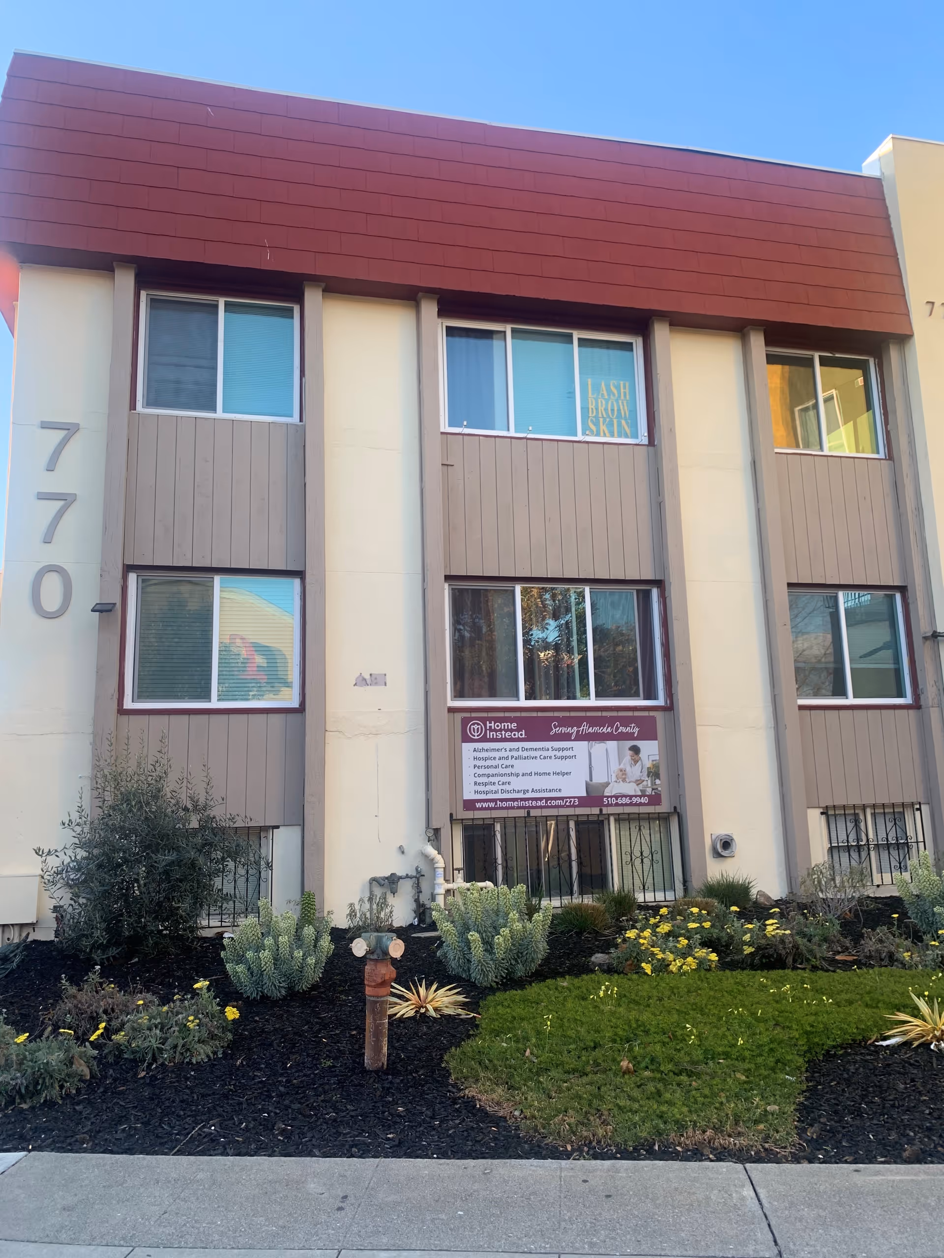 Two-story beige building with brown trim and a Home Instead sign, Castro Valley front landscaping.