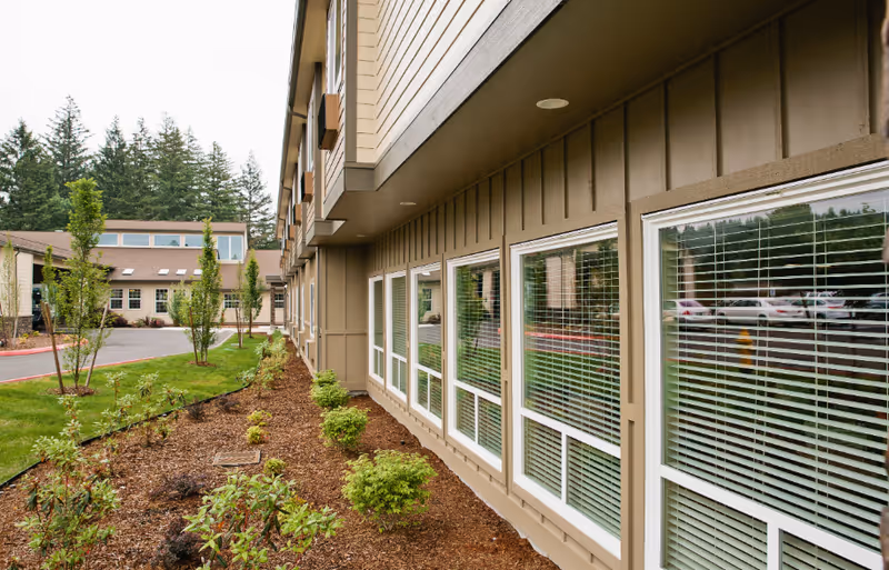 Exterior view of Village Concepts of Chehalis Woodland Village with windows and landscaping.