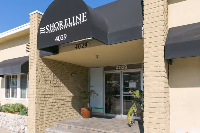 Entrance of Shoreline Healthcare Center with a black awning reading 'SHORELINE HEALTHCARE CENTER' and the address number 4029 above glass doors.