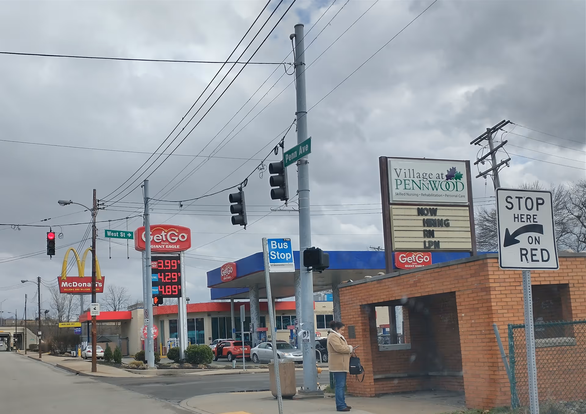 Outdoor street scene with Village at Pennwood sign near a gas station.