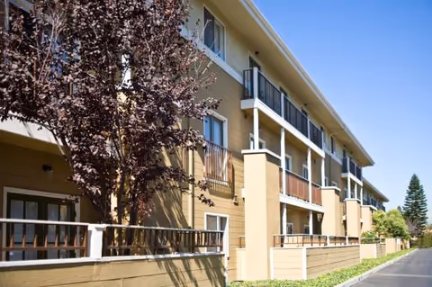 Exterior view of Emerald Court, a multi-story senior living building with balconies and landscaping.
