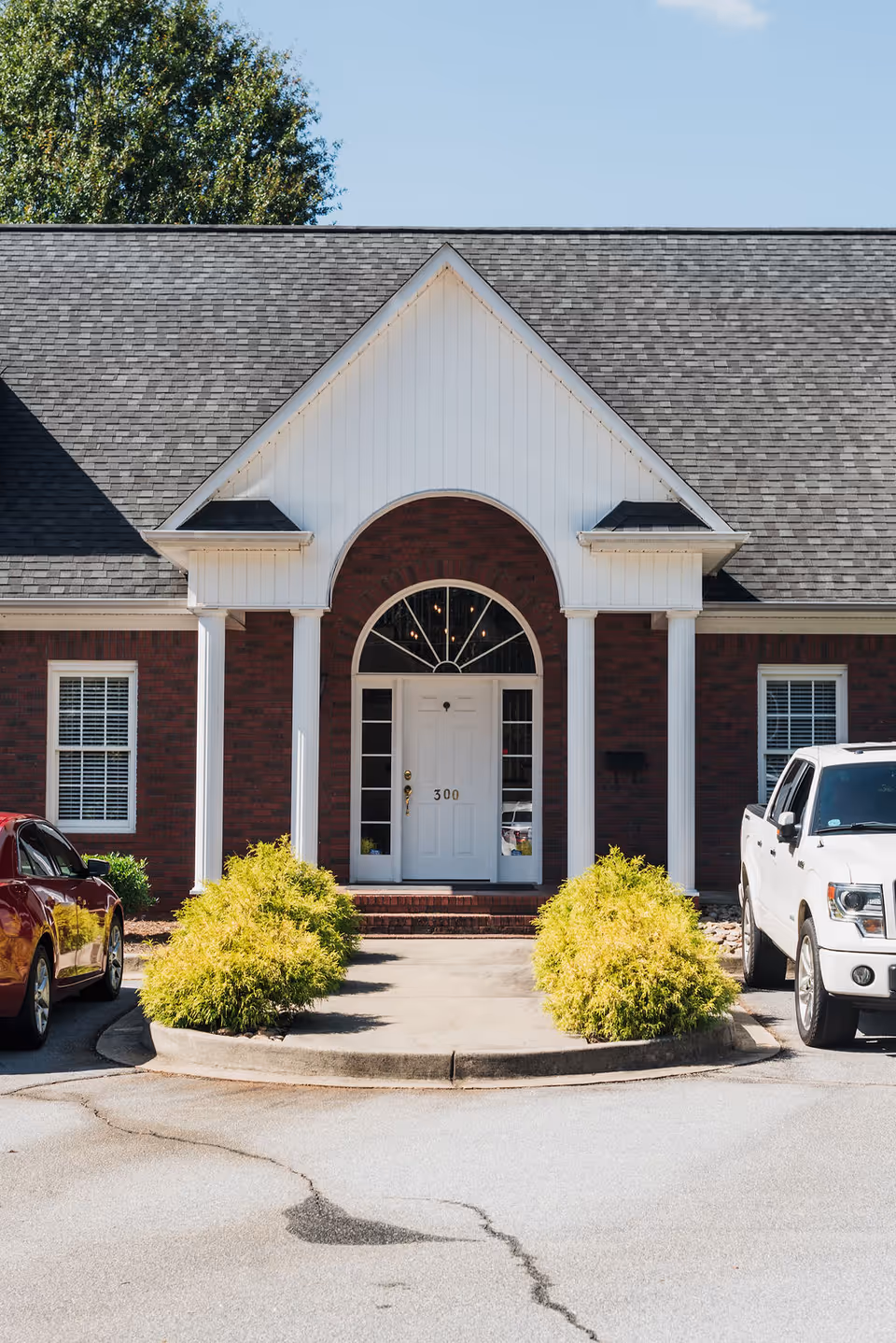 Brick senior living facility front entrance with white door and arched window.