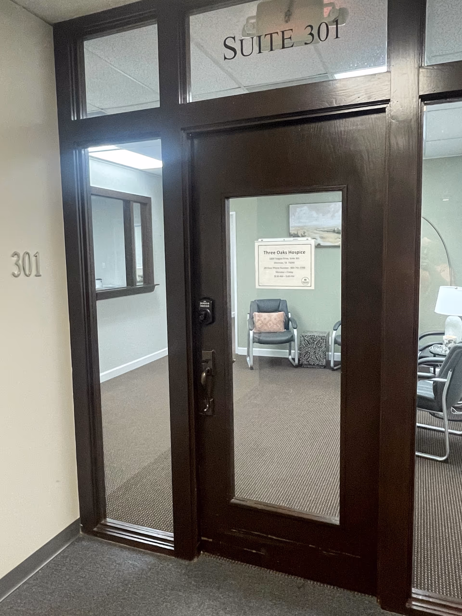 Dark wood door labeled Suite 301 opens to an interior lobby with chairs.