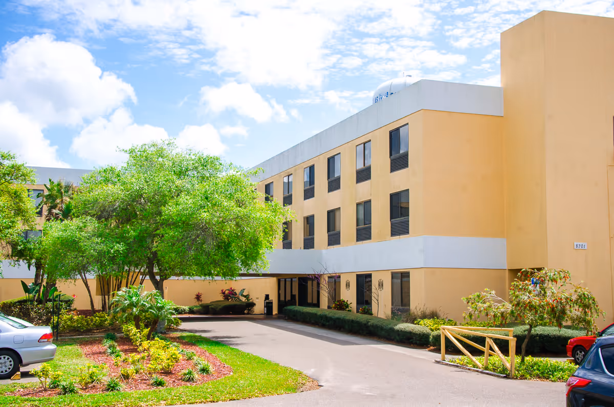 Exterior view of Pinellas Park Post-Acute and Rehabilitation Center with trees and landscaping.
