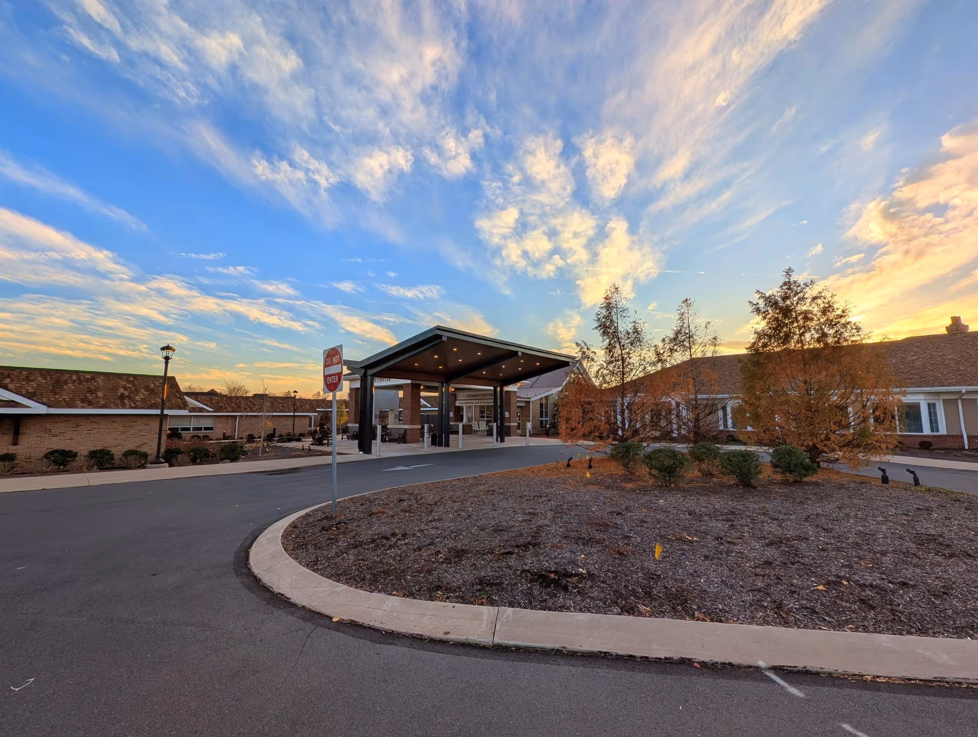 Sunset over RiverWoods Senior Living Community entrance with a covered driveway.