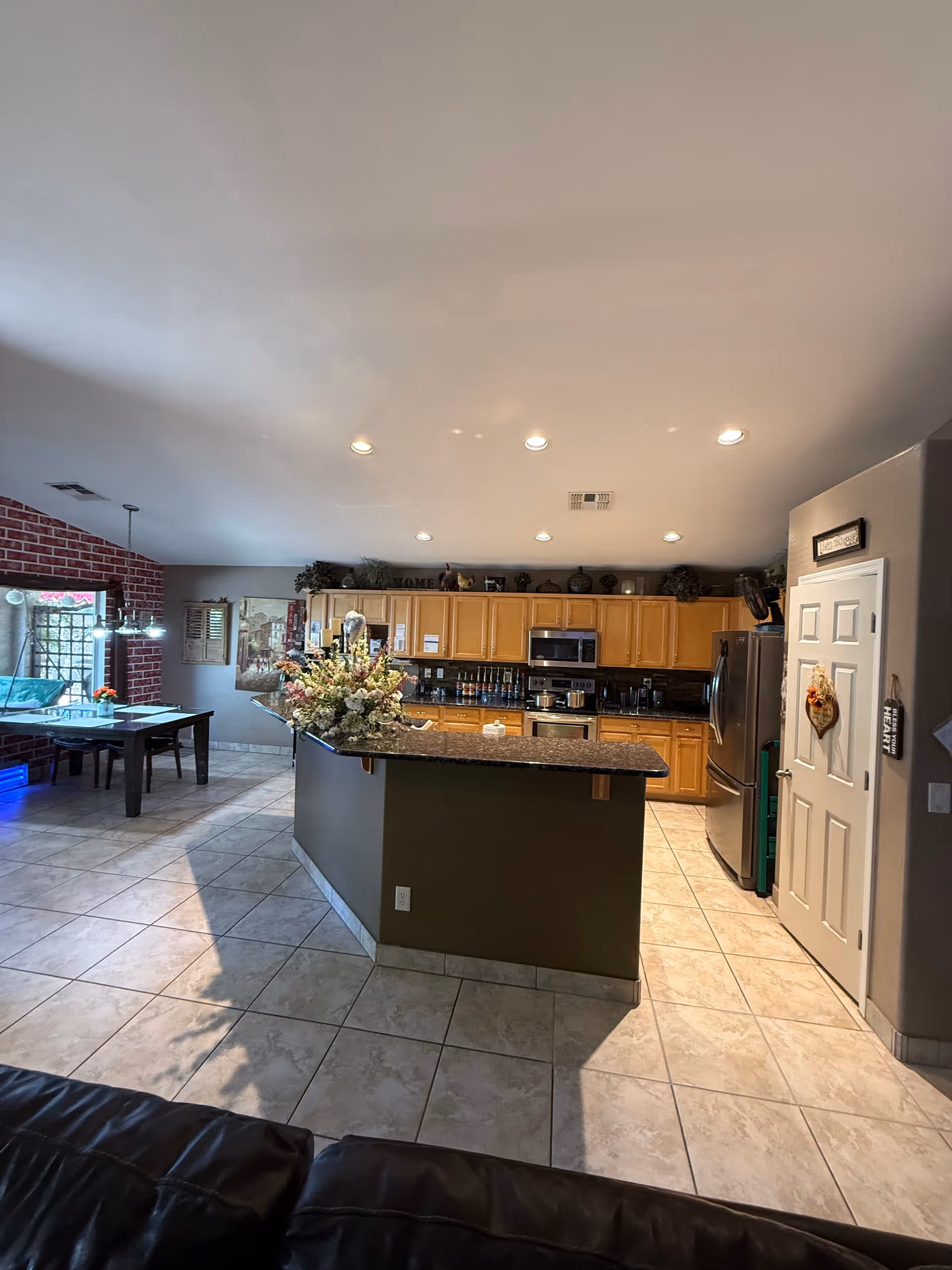 Open-concept kitchen with island, wooden cabinets, and stainless appliances in a senior living common area.
