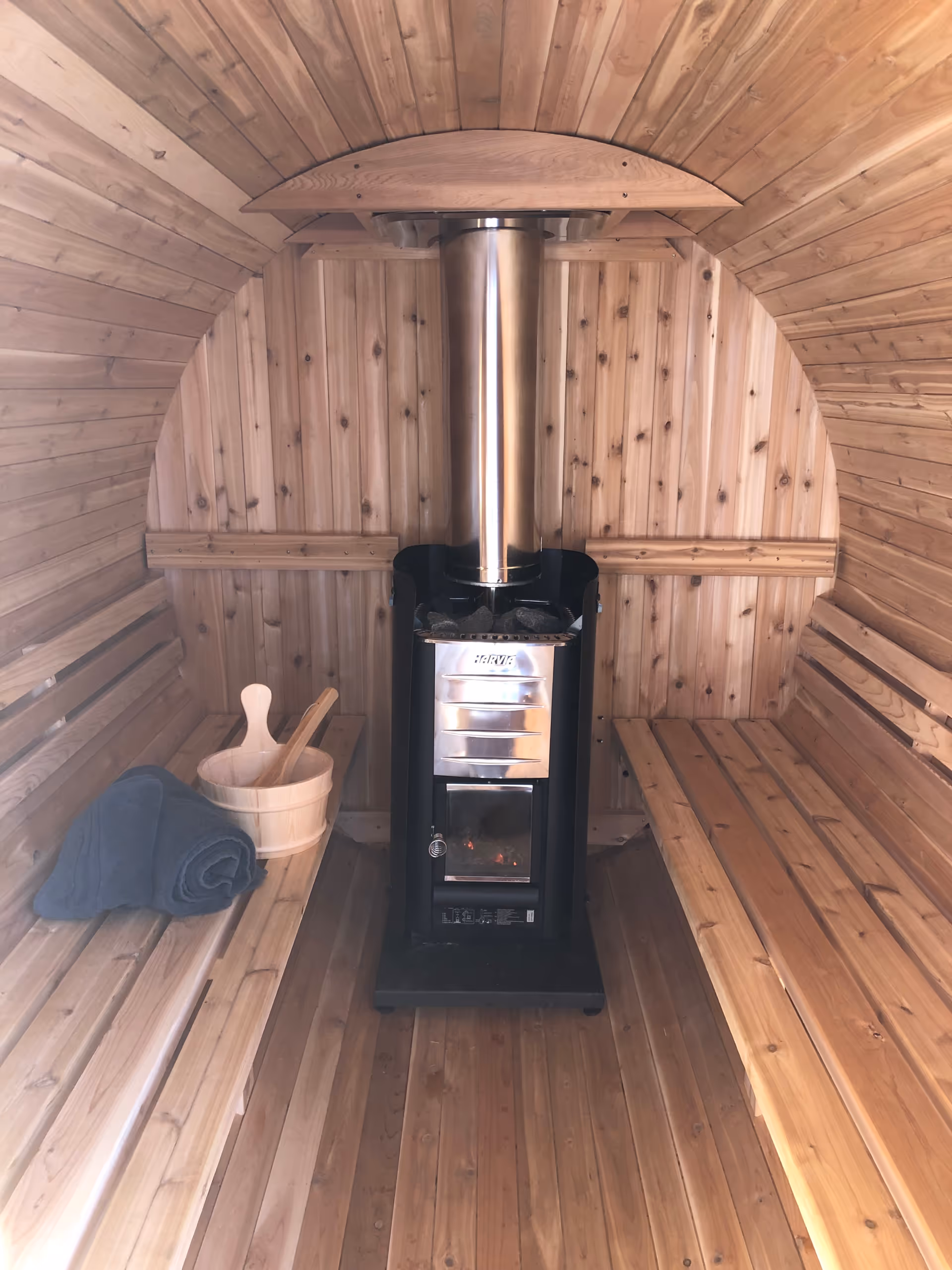 Cozy wooden sauna interior featuring a metal stove and long wooden benches.