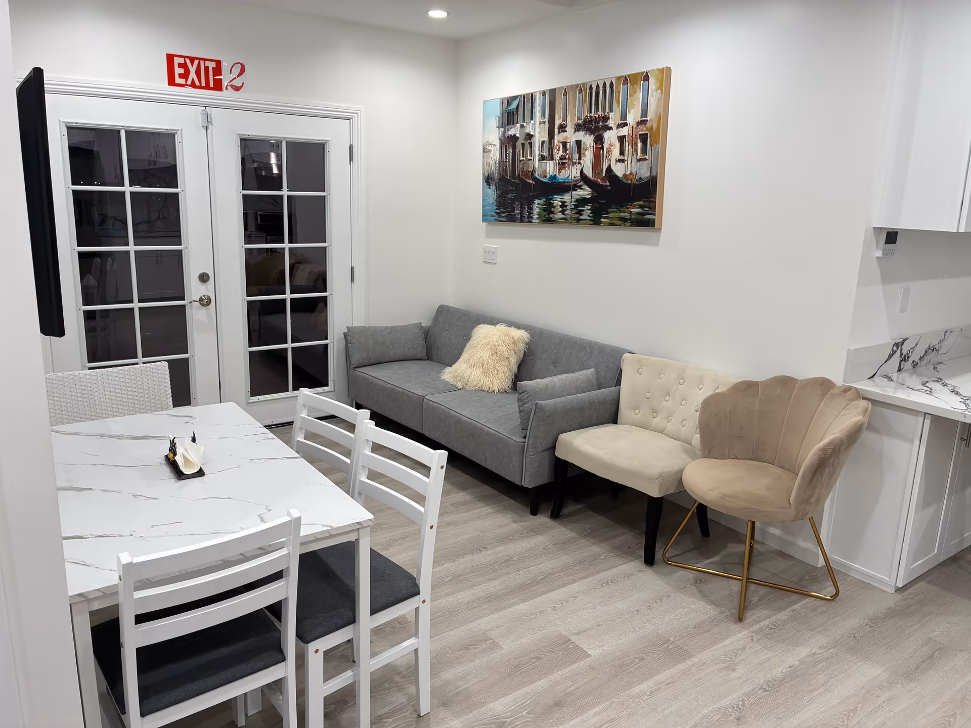 Modern senior living common area with couch, chairs, dining table, and artwork.