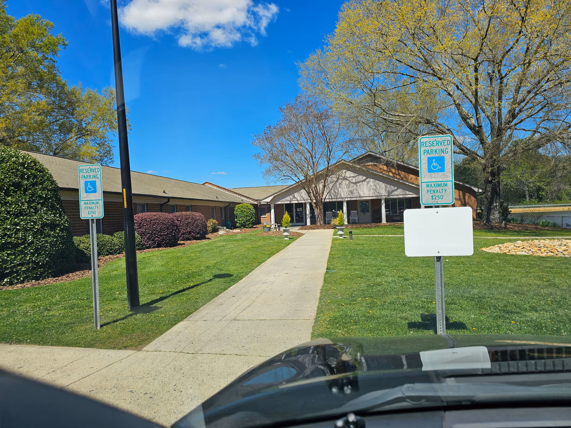 Exterior view of Autumn Care of Biscoe with walkway to entrance and parking signs.