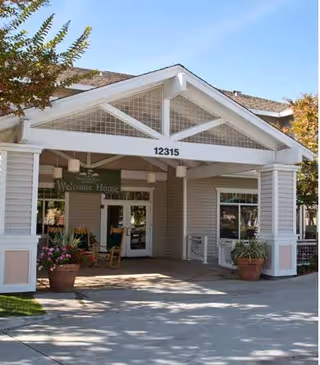 Senior living center entrance with covered front porch and potted plants.