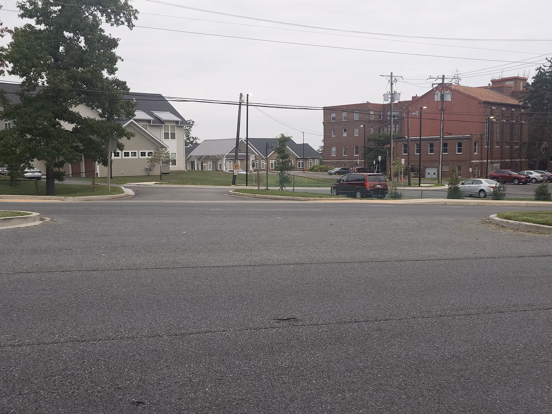 A street scene with parked cars and brick buildings along power lines.