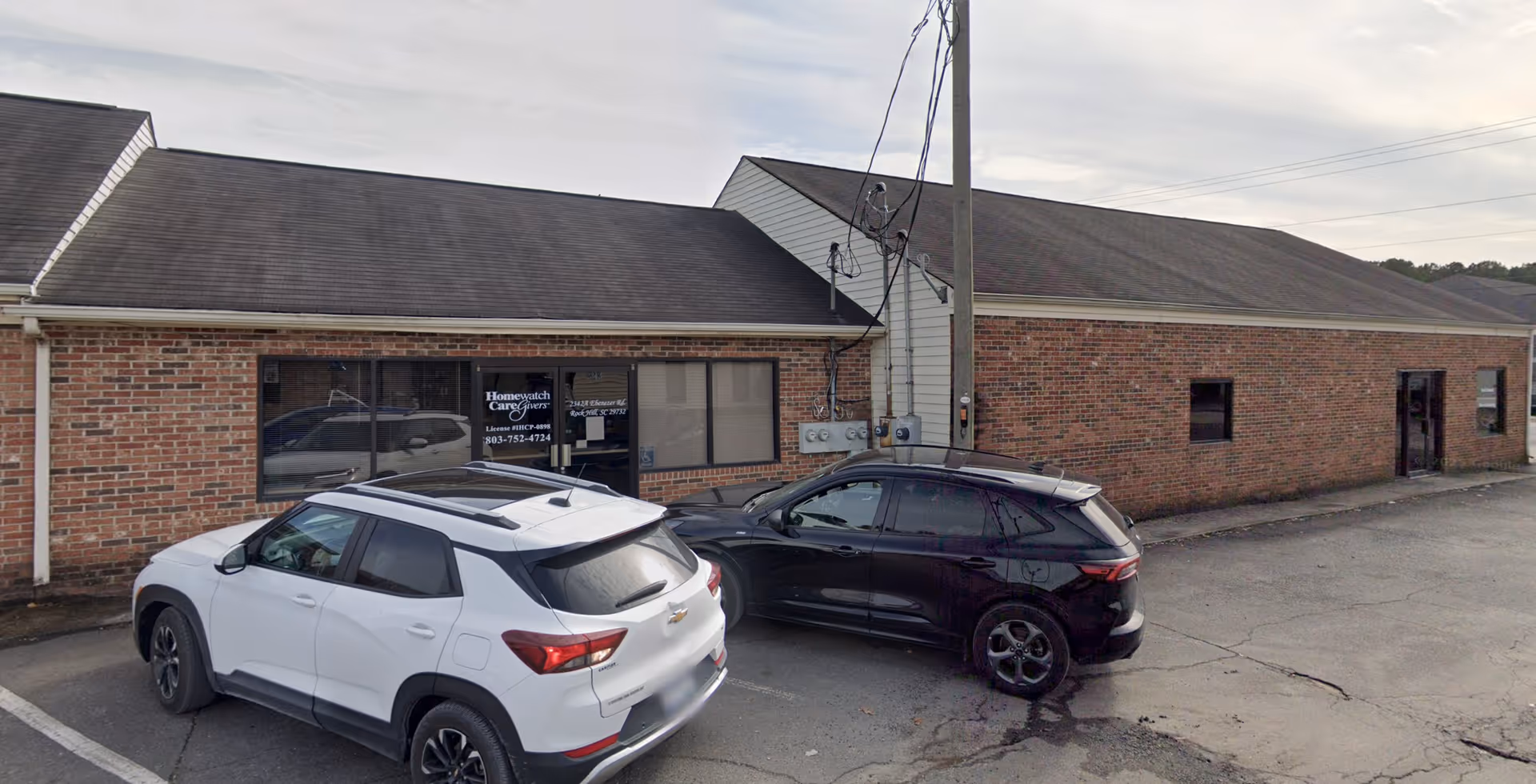 Exterior view of a brick facility with two parked cars in front, Homewatch CareGivers.