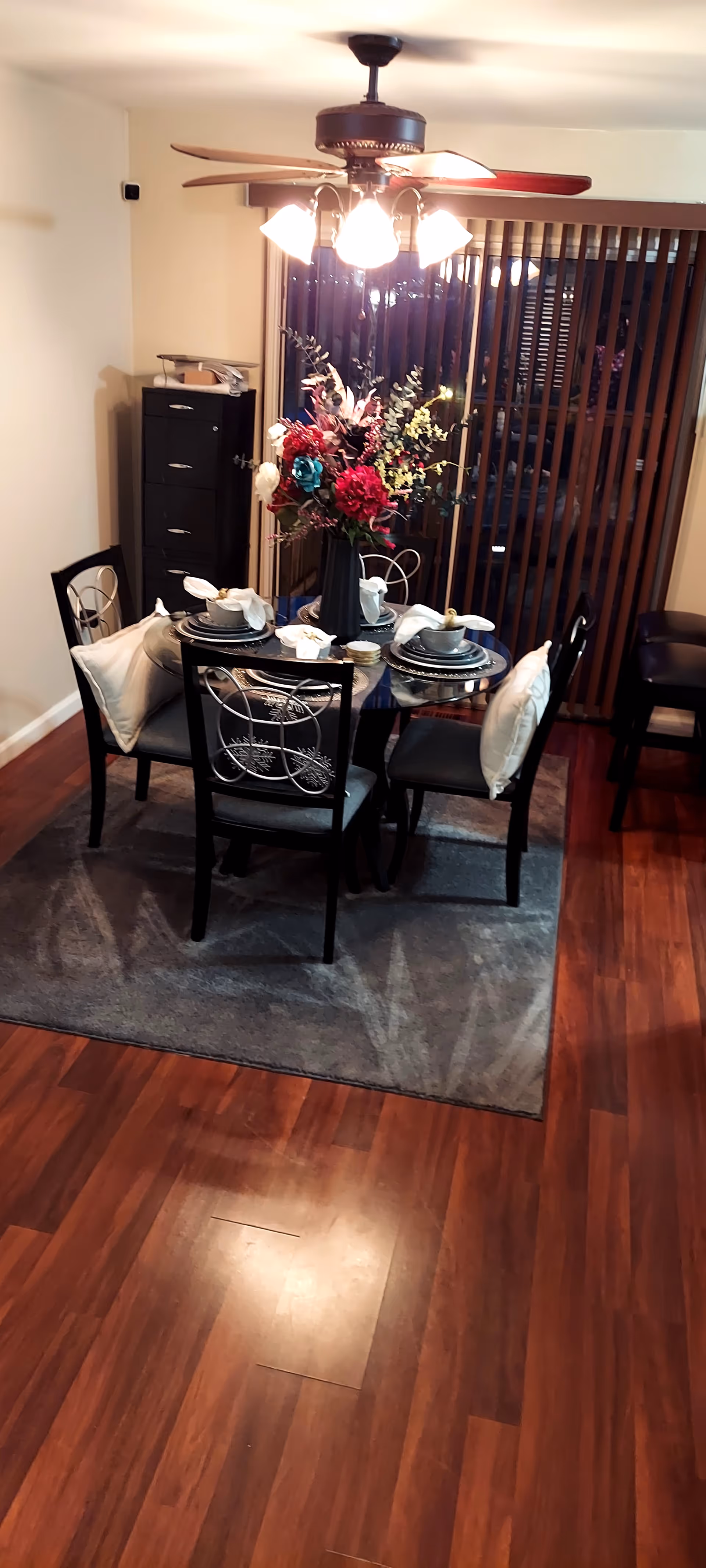 Dining room with a dark wood table set for four, centerpiece, and ceiling fan.