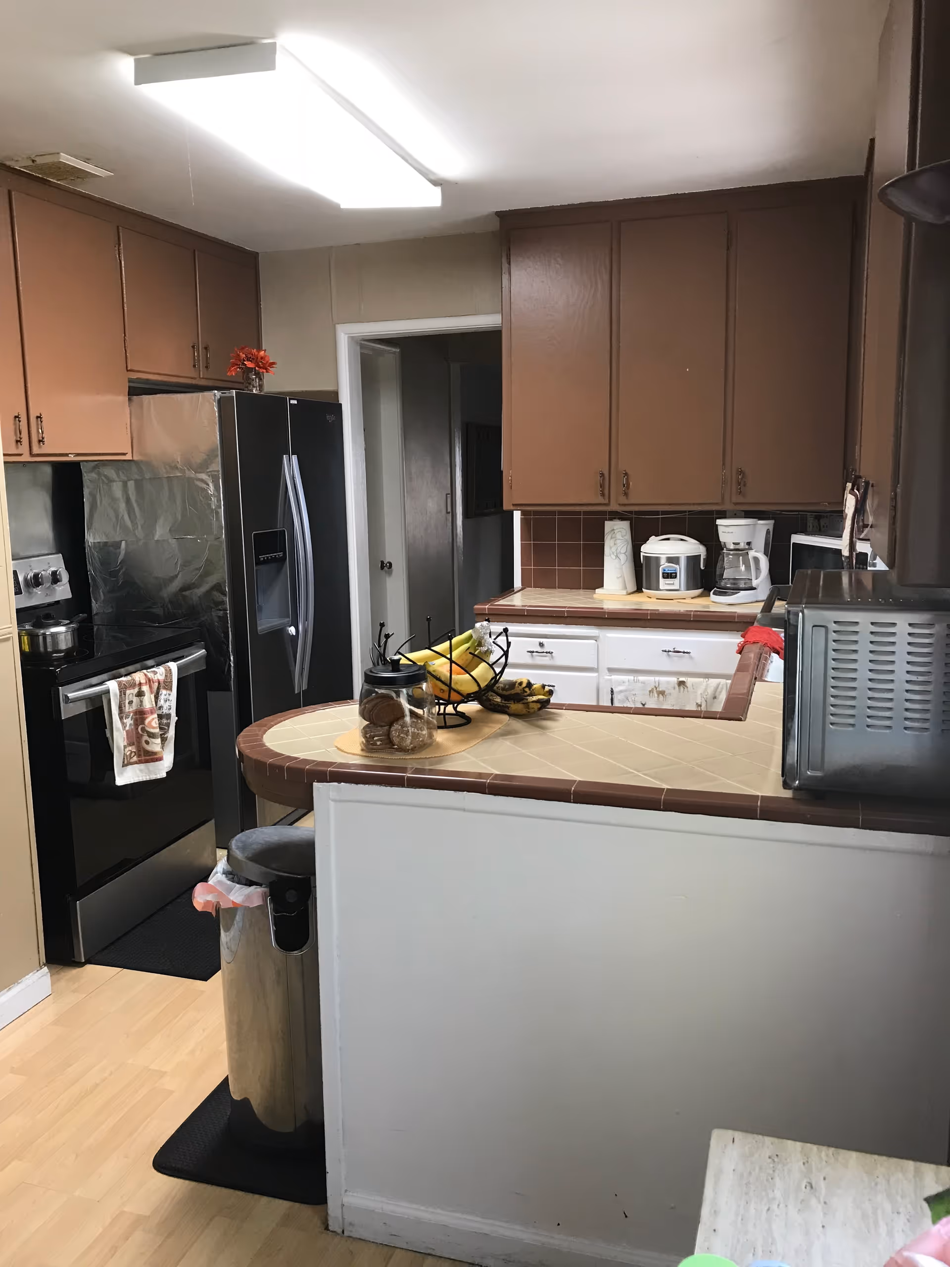 Open kitchen in a senior living facility with brown cabinets and a central tiled island.