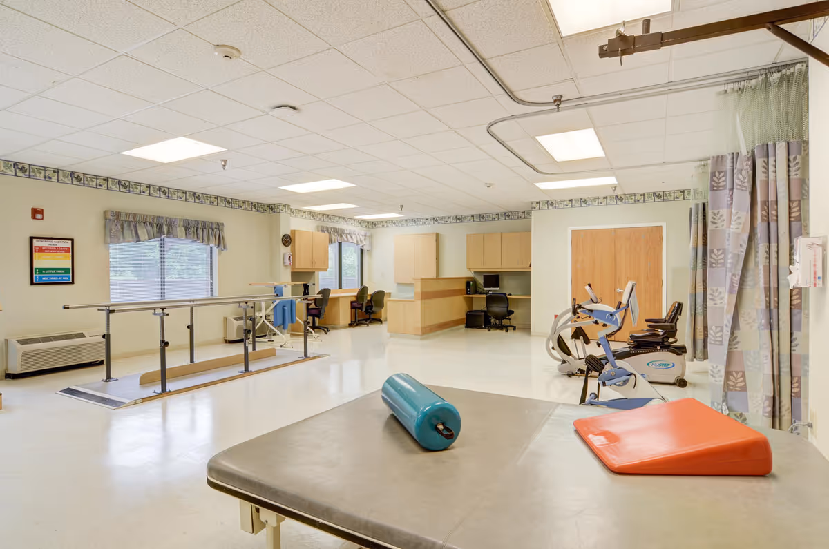Therapy gym inside South Hills Post Acute featuring parallel bars, a bike, and a therapy table.