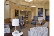 Interior lounge with sofas, chairs, and tables in a senior living facility common area.