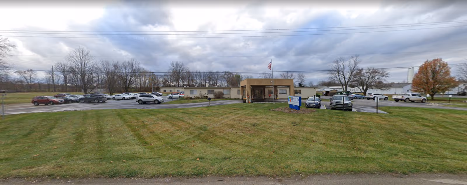 Front exterior view of Ovid Health Care Ctr building with parking lot and a grassy lawn.