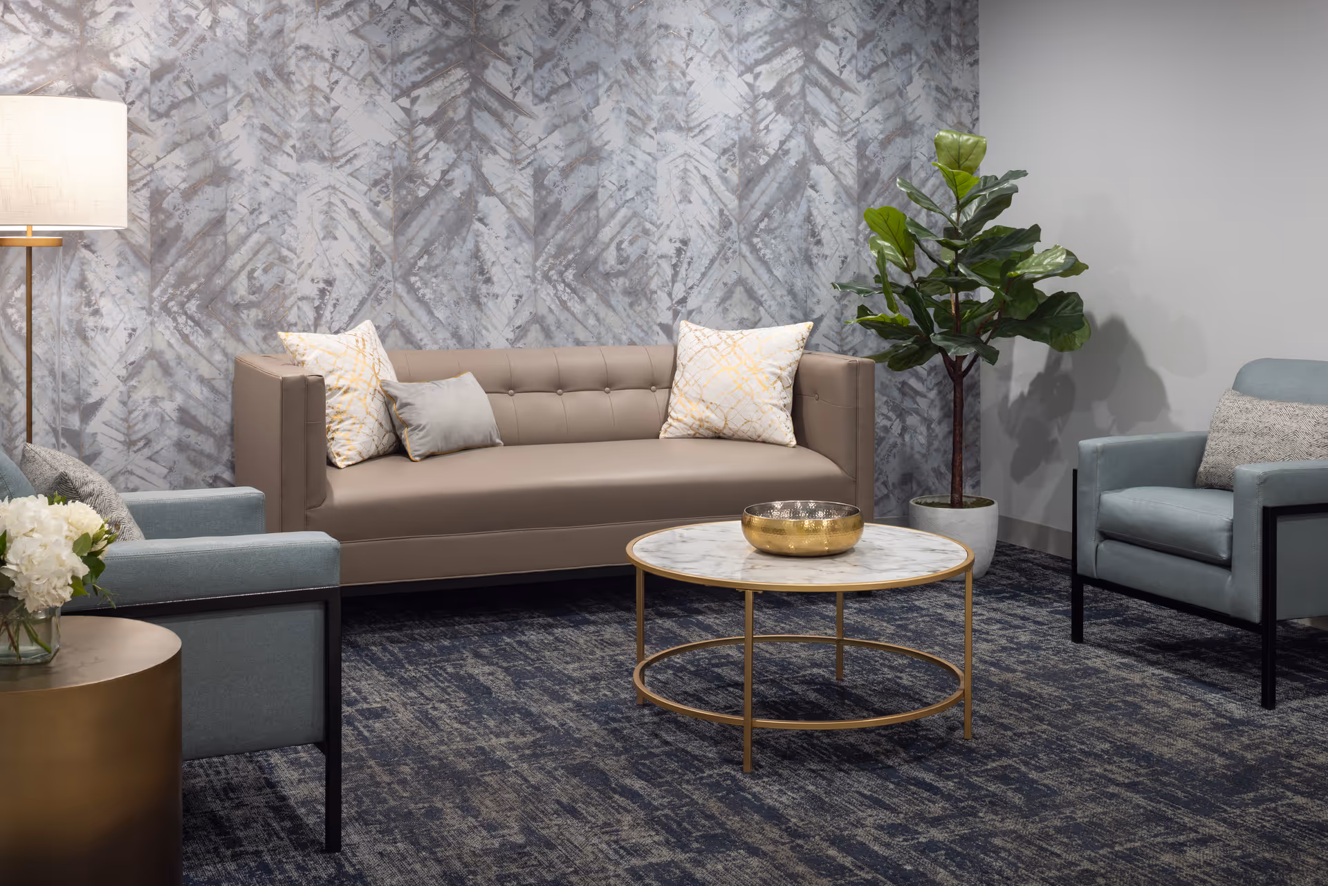 A modern living room seating area with sofa, chairs, and a round coffee table.