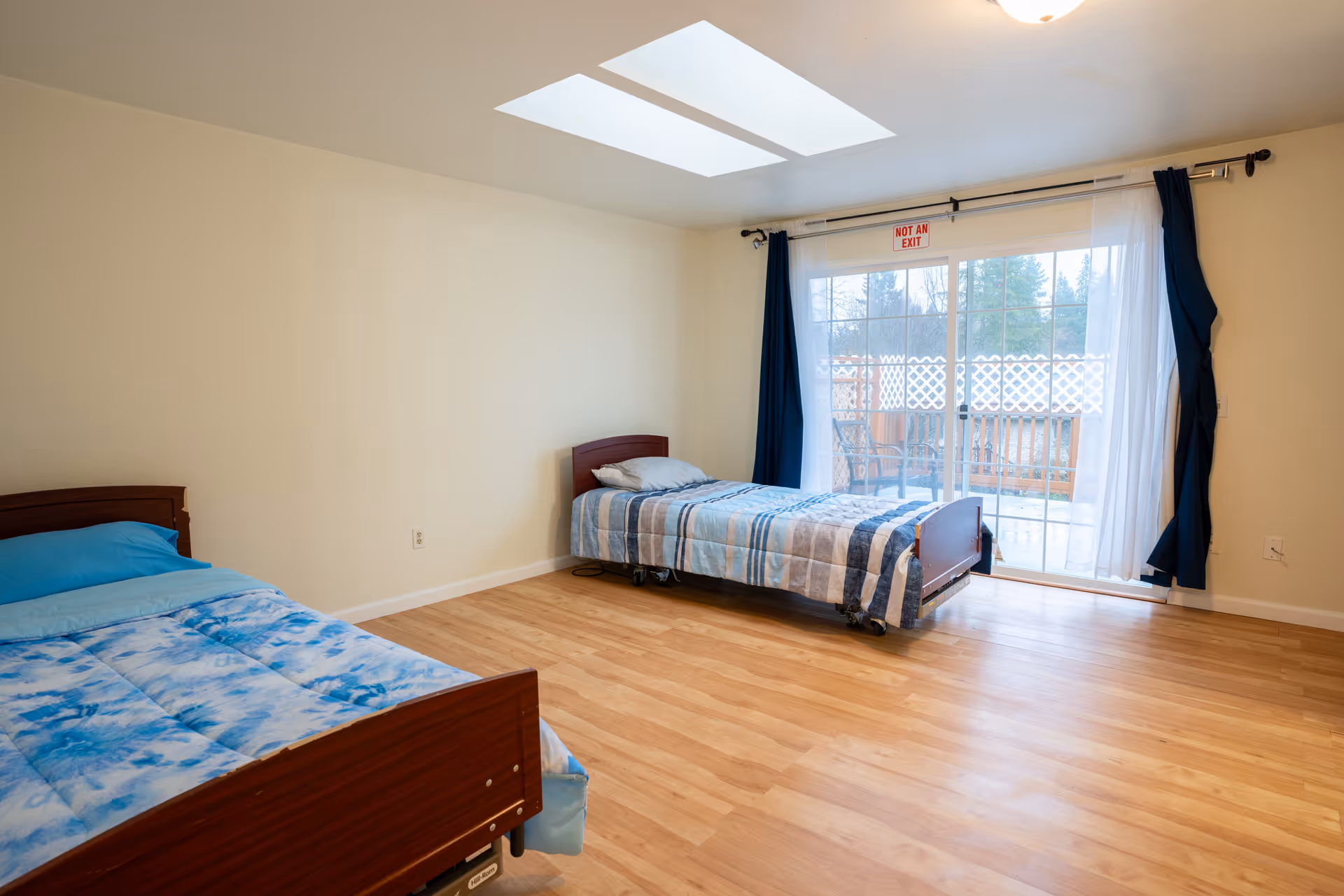 Two single beds in a bright bedroom with sliding door to an outdoor deck.