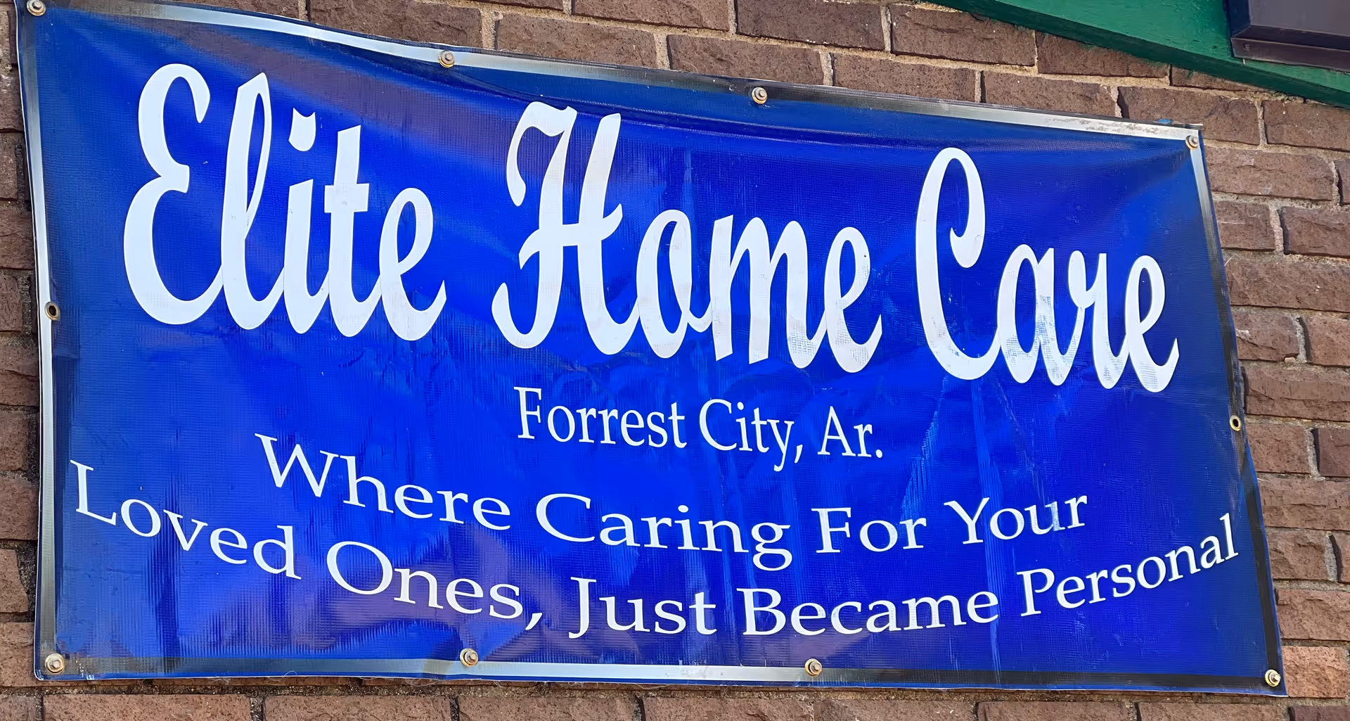 Blue Elite Home Care banner on brick wall storefront reads Forrest City, AR.