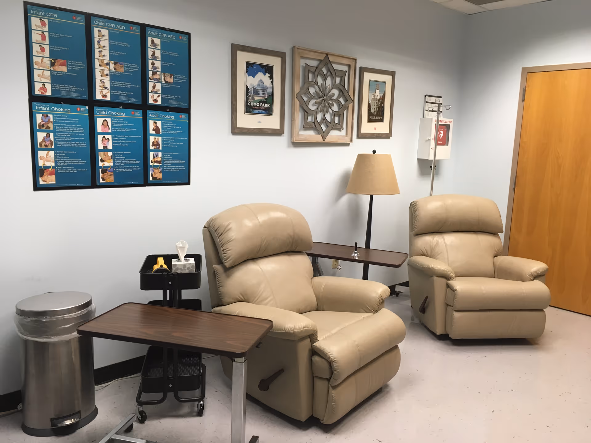 Small lounge area with two beige recliner chairs, side tables, lamp, and wall art.