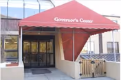 Red canopy labeled Governor's Center over glass doors at building entrance.