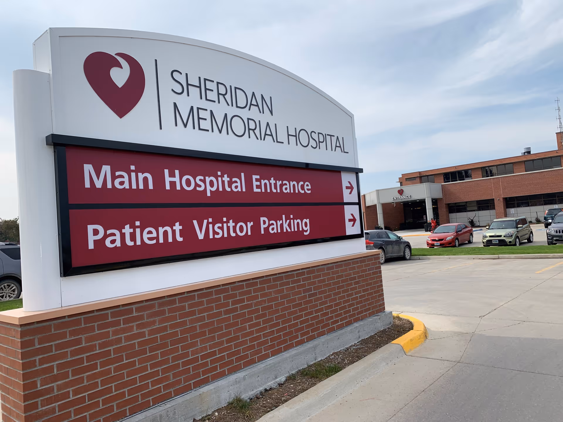 Exterior view of Sheridan Memorial Hospital sign with main entrance and parking.