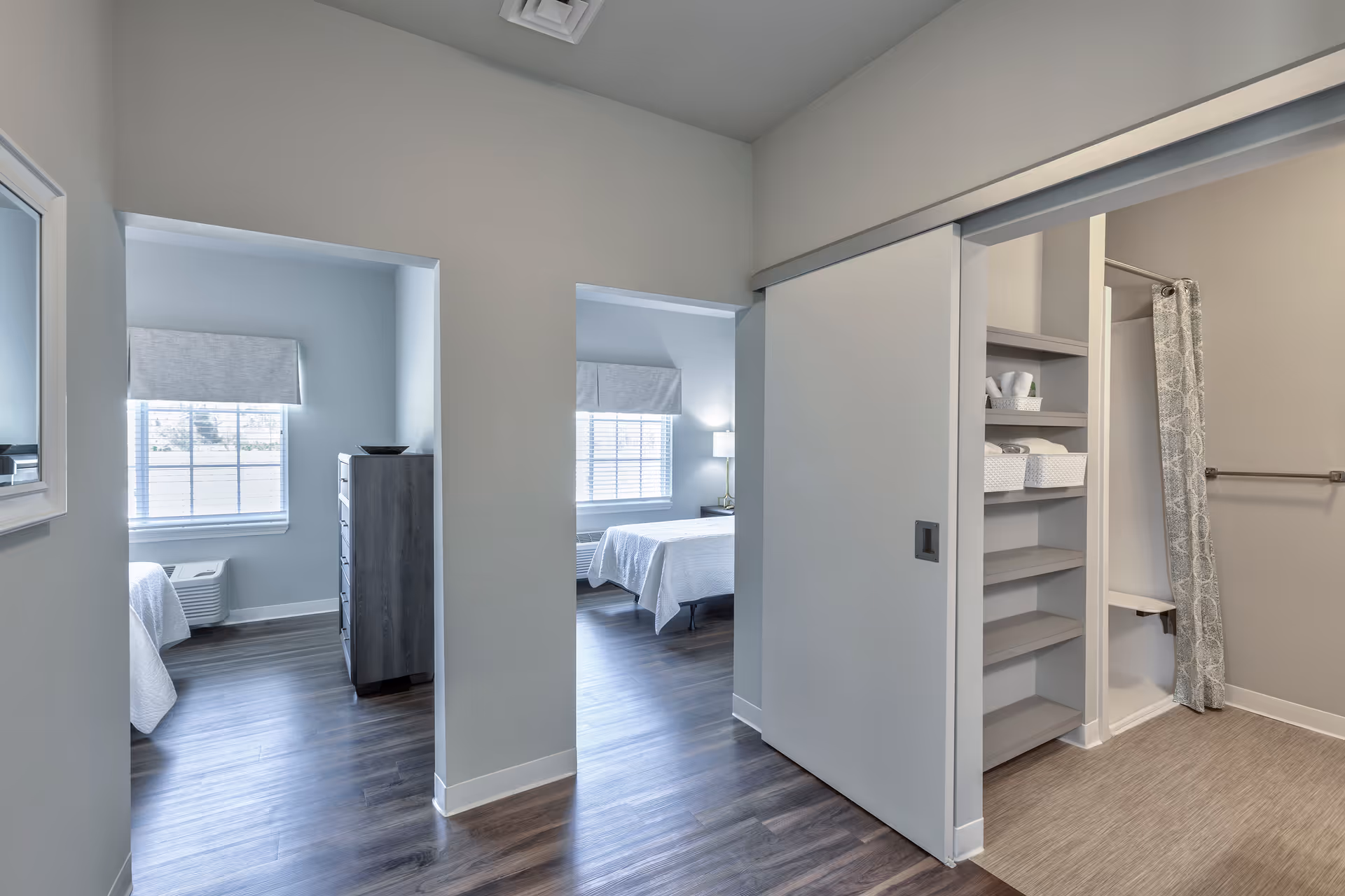Interior hallway with two adjoining bedrooms featuring beds and a closet area.
