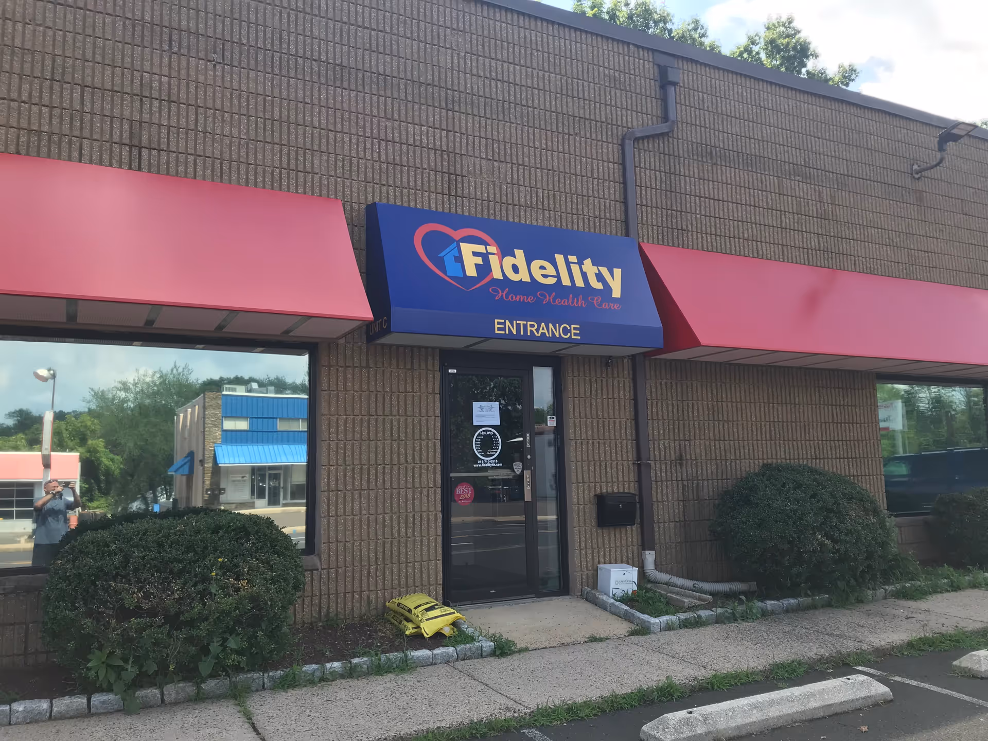 Exterior view of Fidelity Home Health entrance with blue sign and pink awnings.
