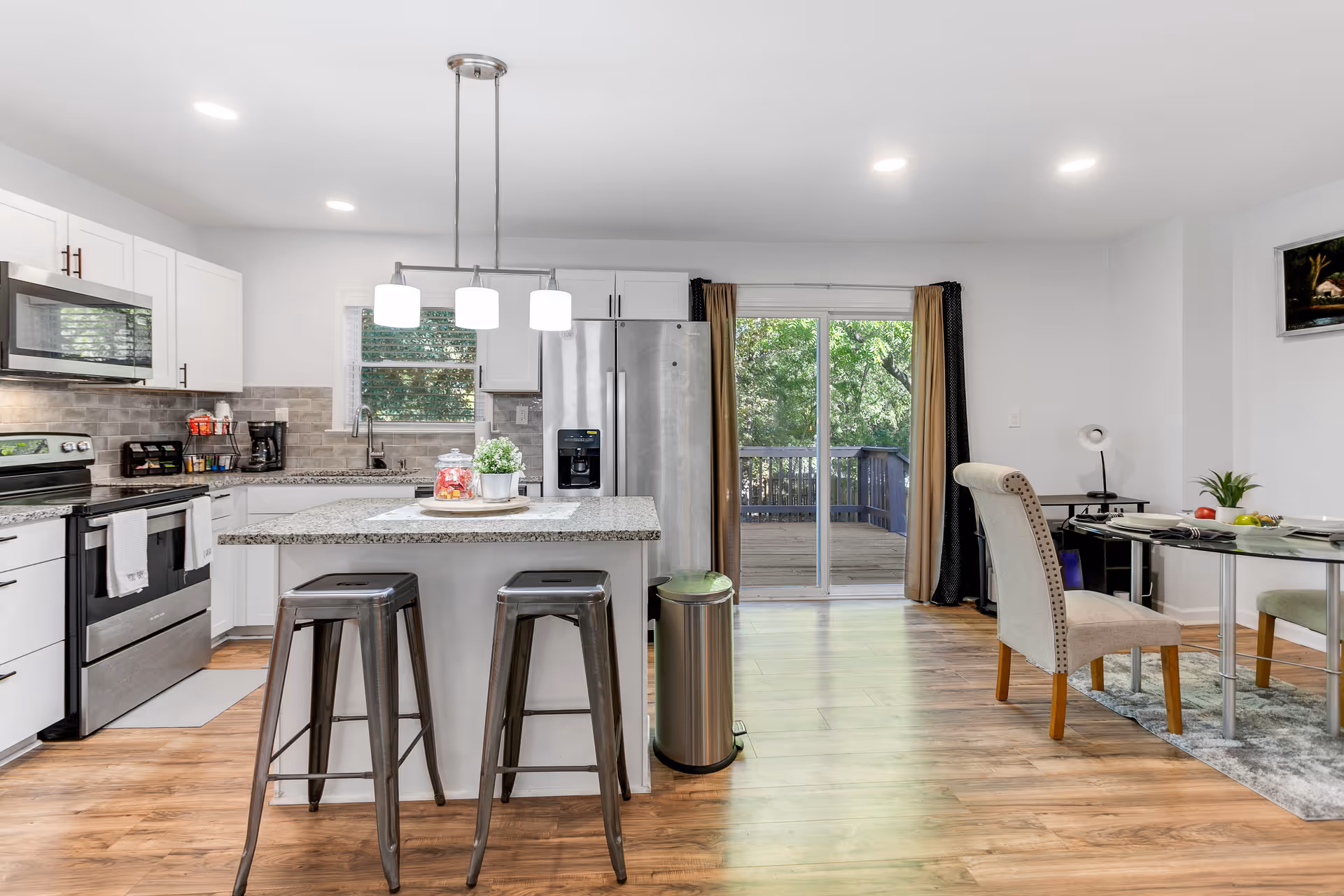 Open-concept kitchen with island, stainless appliances, and a dining table near sliding doors.