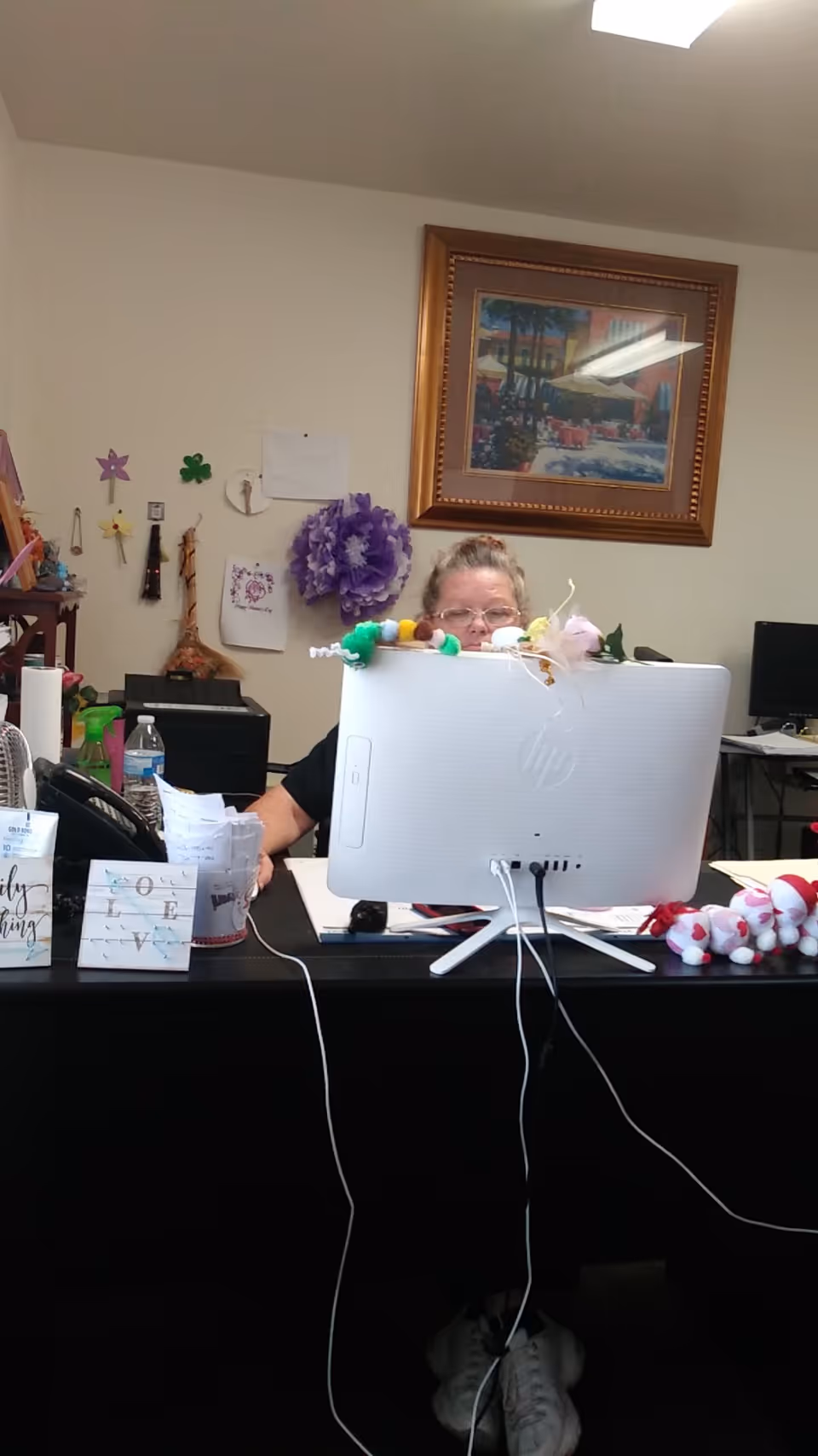 Staff member sits at a desk with a computer monitor and festive decorations.
